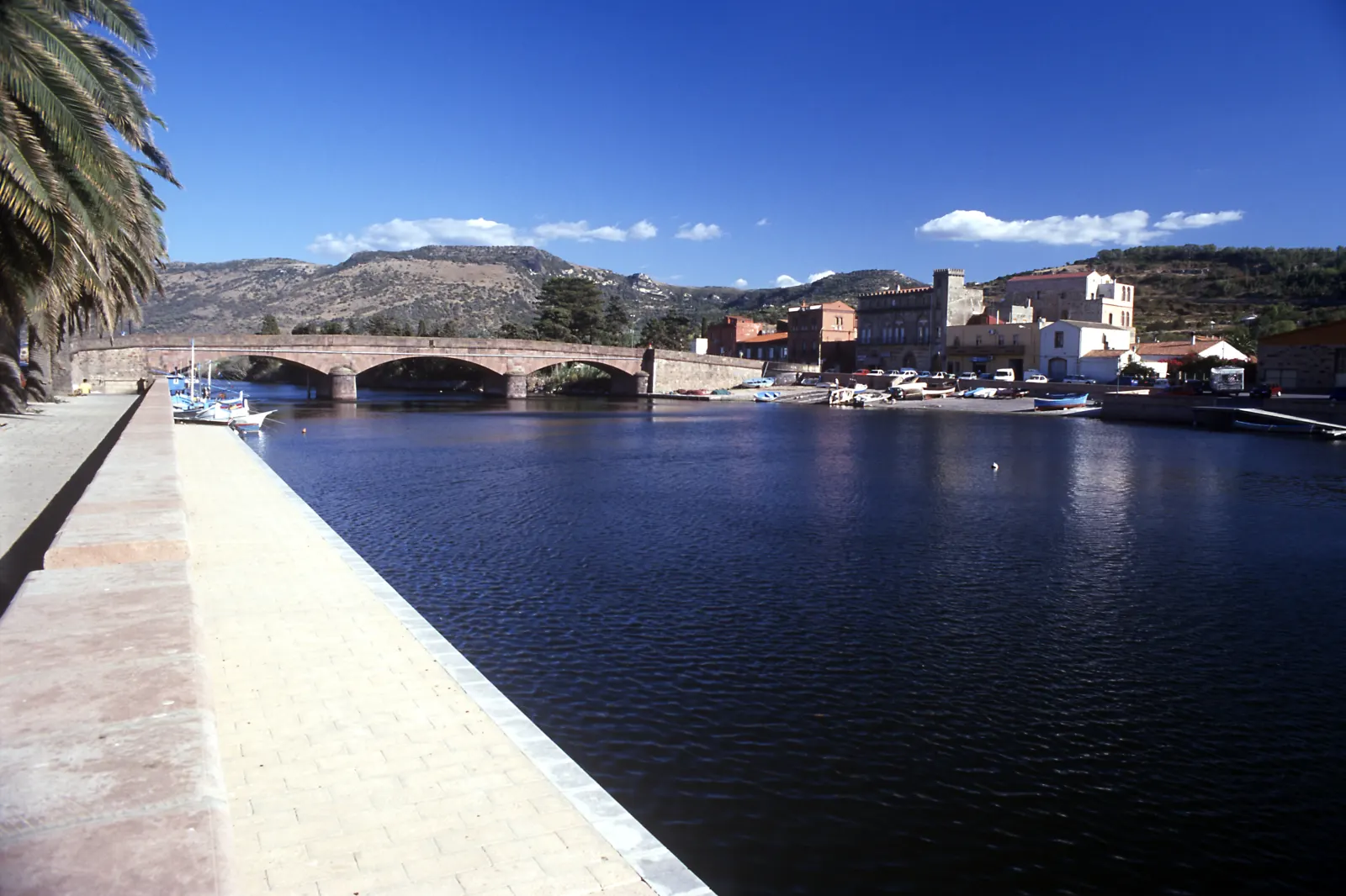 Il Ponte Vecchio in trachite rossa sul fiume Temo a Bosa, con le barche ormeggiate lungo le sponde