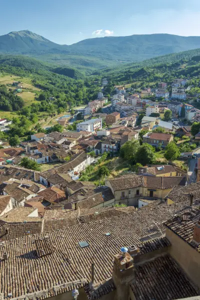 I tetti in coppi del centro storico di Calvello e la valle boscosa che scende verso le montagne lucane