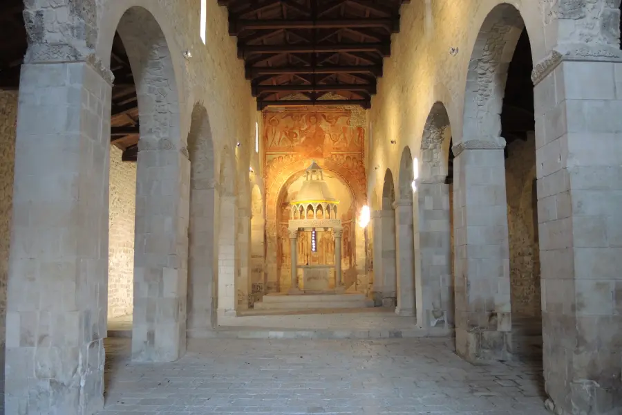 L’interno a tre navate di San Pietro ad Oratorium con le colonne in pietra e l’abside affrescata