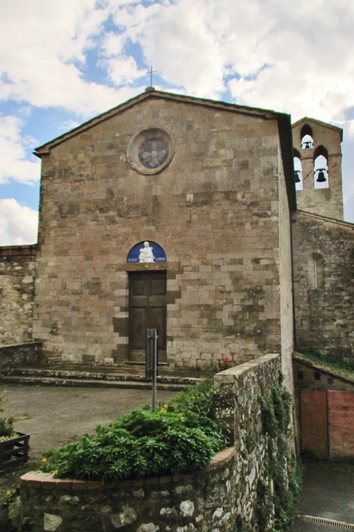 La facciata in pietra arenaria della Pieve di San Giovanni Battista a Querceto, con la maiolica sul portale