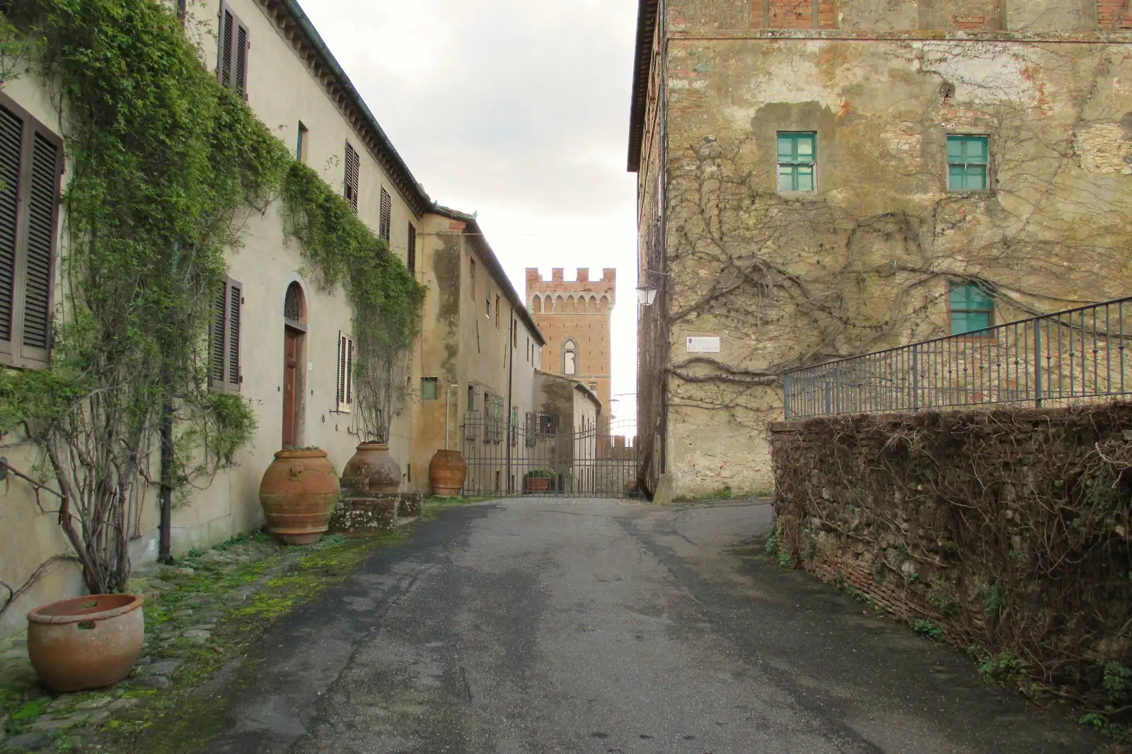 Una via di Querceto con le case in pietra e la torre merlata del Castello Ginori sullo sfondo
