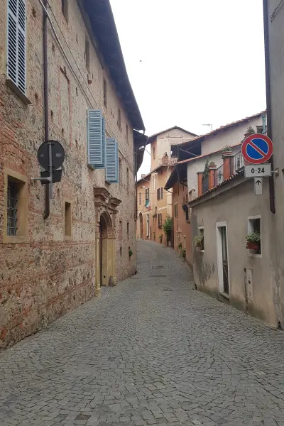 Strada del centro storico di Romano Canavese con case in pietra e mattoni e un portale barocco