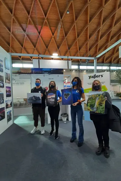 Quattro ragazzi di Yallers allo stand del TTG mostrano le stampe fotografiche dei loro scatti
